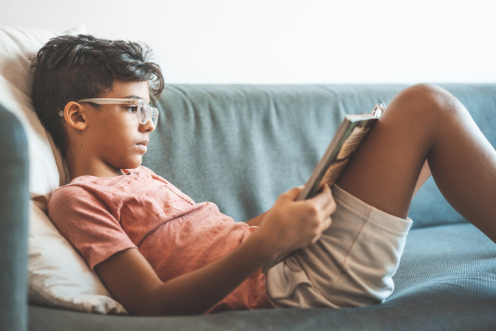Boy reading book on sofa