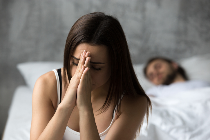 Young woman upset with man in the background.