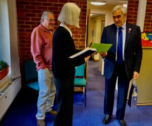 CEO of Victim Support Diana Fawcett presenting volunteer Derek Radley with a bottle of wine and letters of support for his British Empire Medal.