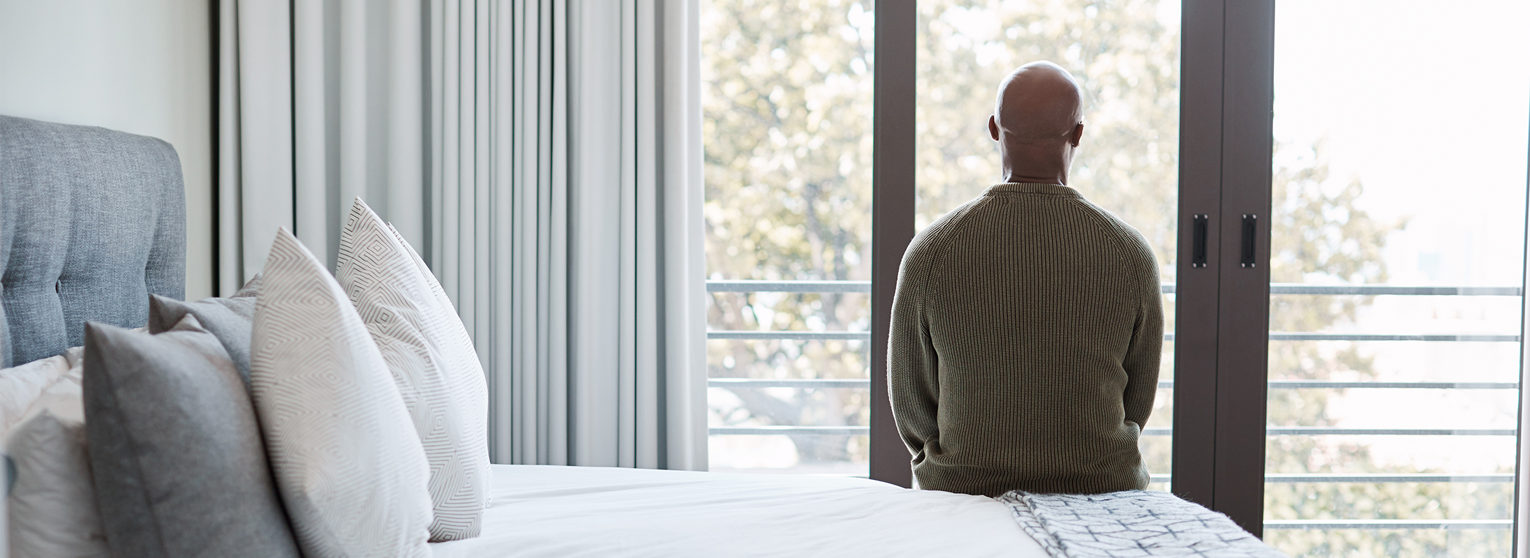Man sitting on bed looking out of window