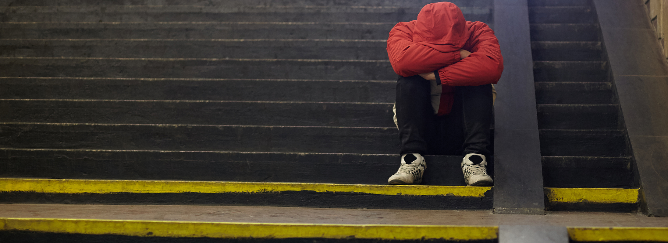 Youth sitting on steps in red jacket