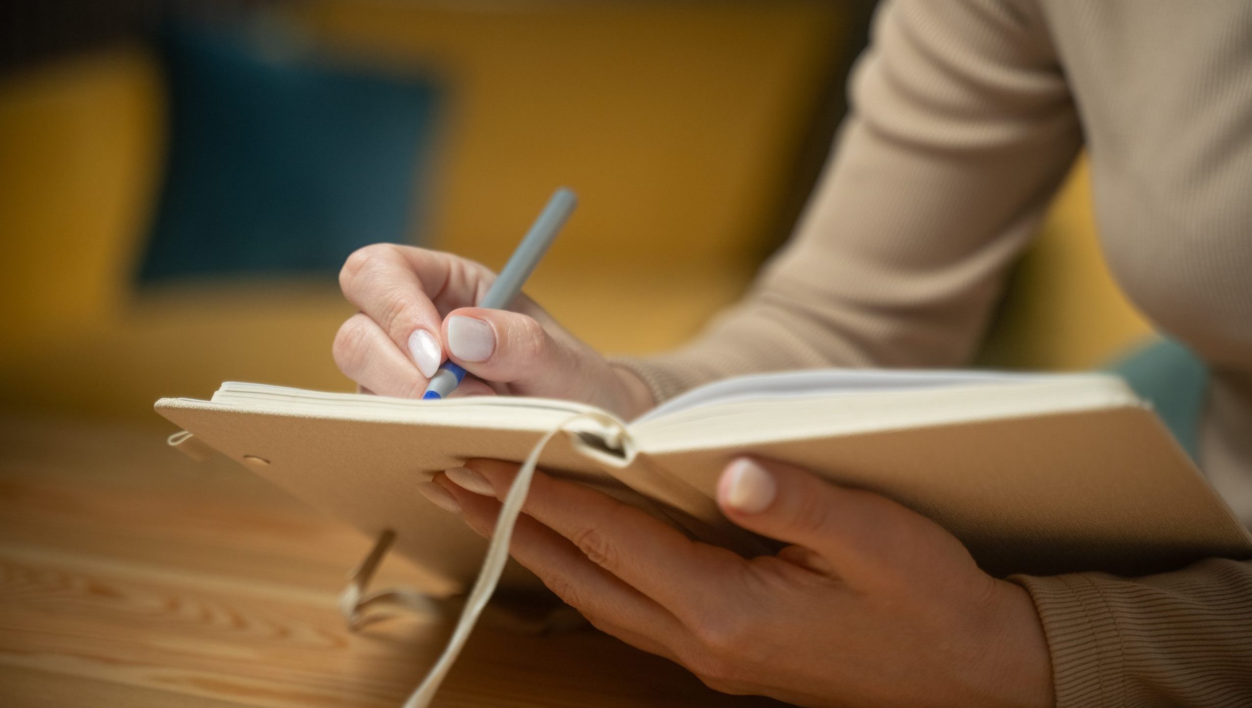 A photo showing a close-up of a person writing in an open notebook
